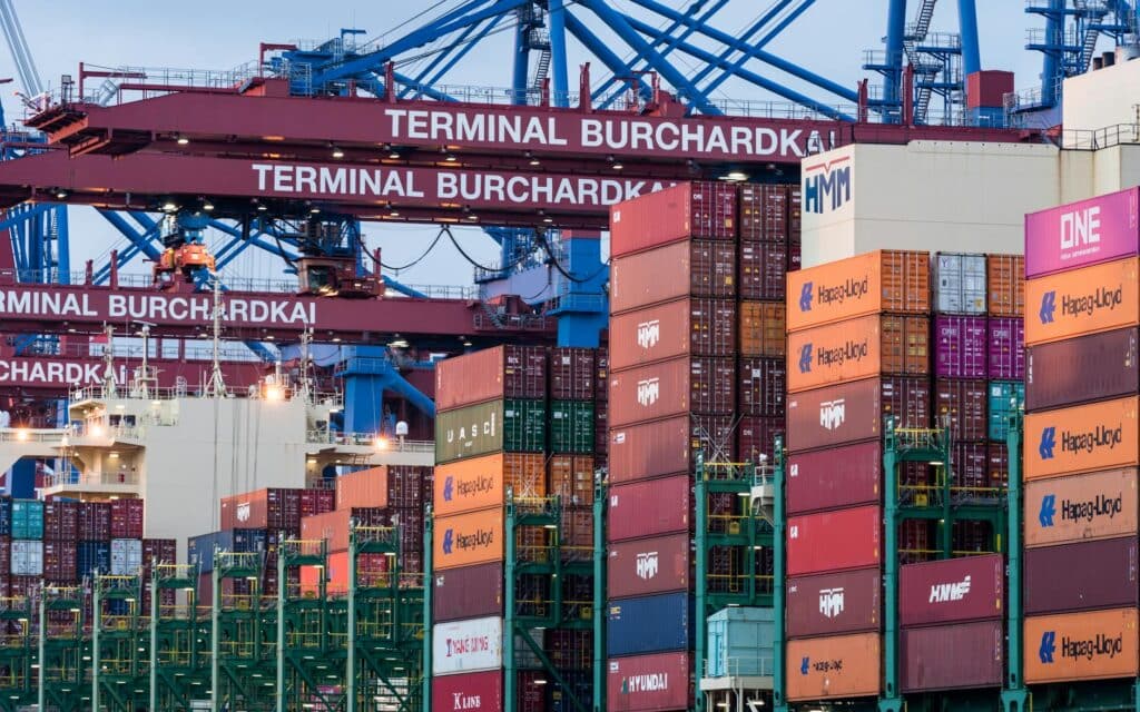 Terminal portuário com contêineres e guindastes — o imposto de importação incide na entrada da mercadoria no Brasil