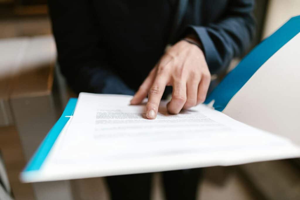 Pessoa apontando texto em documento aberto sobre clipboard azul — passo a passo de habilitação no RADAR Siscomex